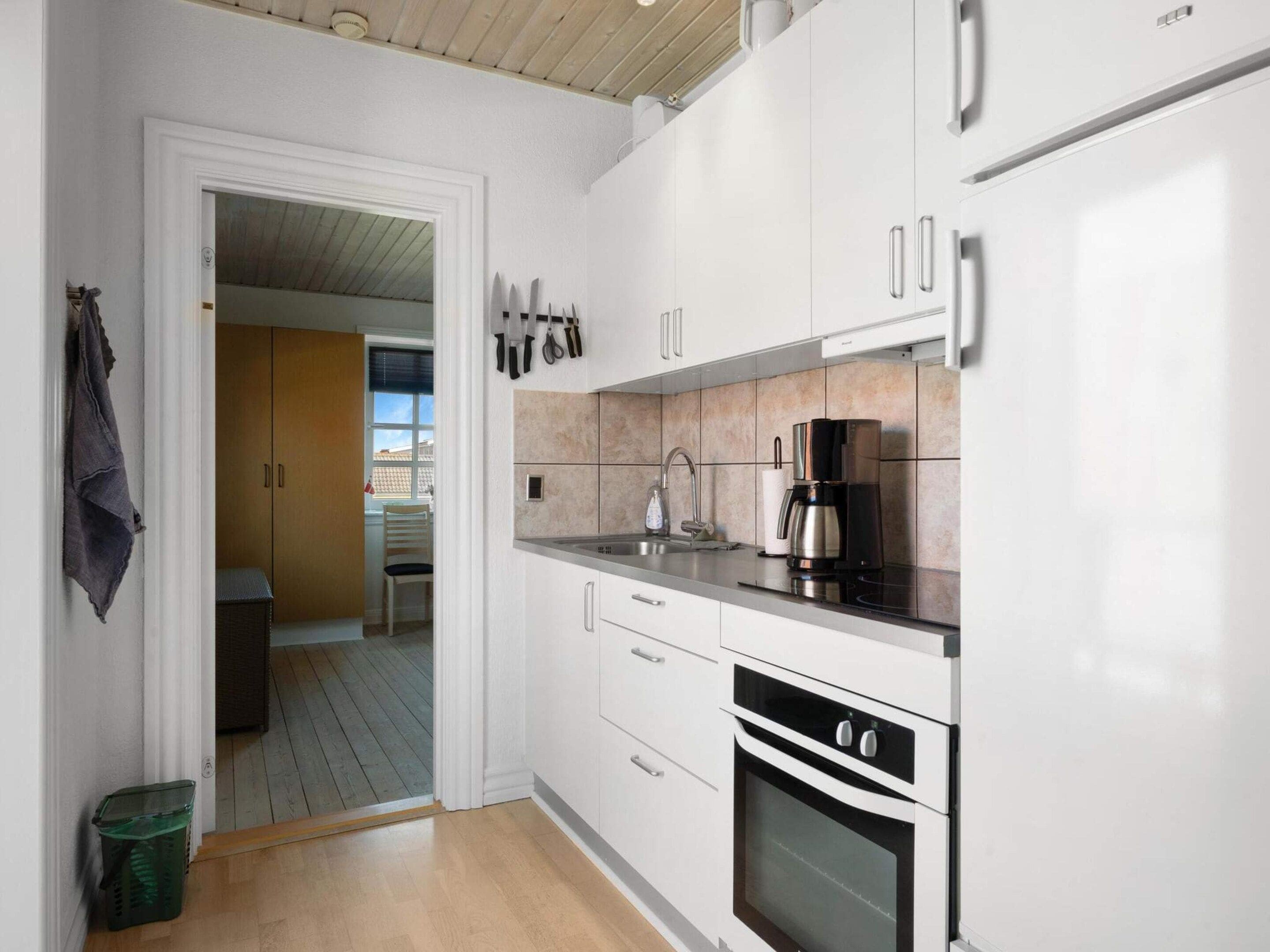 A modern kitchen with white cabinets, a stainless steel oven, and a coffee maker.