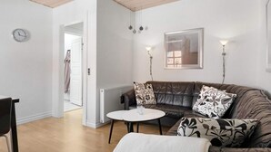 A modern living room with a leather sofa, a round white coffee table, and a clock on the wall. - 5 Star Holiday Home in Lokken (Lokken)