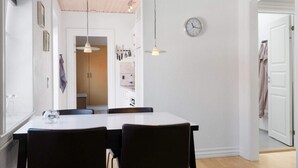 A modern kitchen with a white countertop, two black chairs, a hanging light fixture, and a clock on the wall. - 5 Star Holiday Home in Lokken (Lokken)