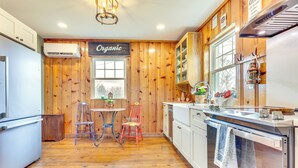 Una cocina con paredes de madera, un comedor con dos sillas, un refrigerador, un horno y un lavamanos.