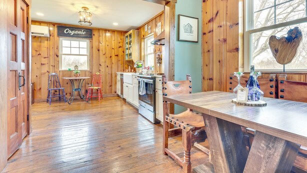 Interior de madera con una cocina, una mesa de comedor y una decoración con forma de corazón en la ventana.
