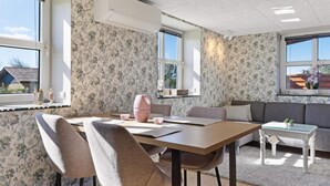 Un salon moderne comprenant un coin repas, un papier peint à motifs floraux, un canapé et une table avec des chaises.