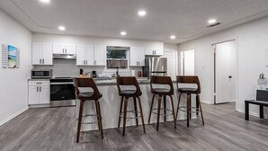 Eine moderne Küche mit weißen Schränken, Edelstahlgeräten und einer Holztheke mit Barhocker.