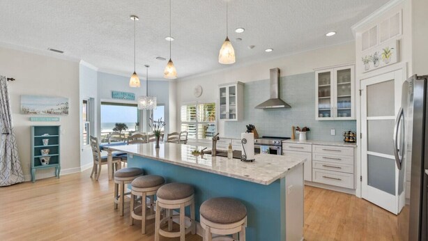 Una cocina moderna con una isla central, taburetes de bar y vistas al exterior.