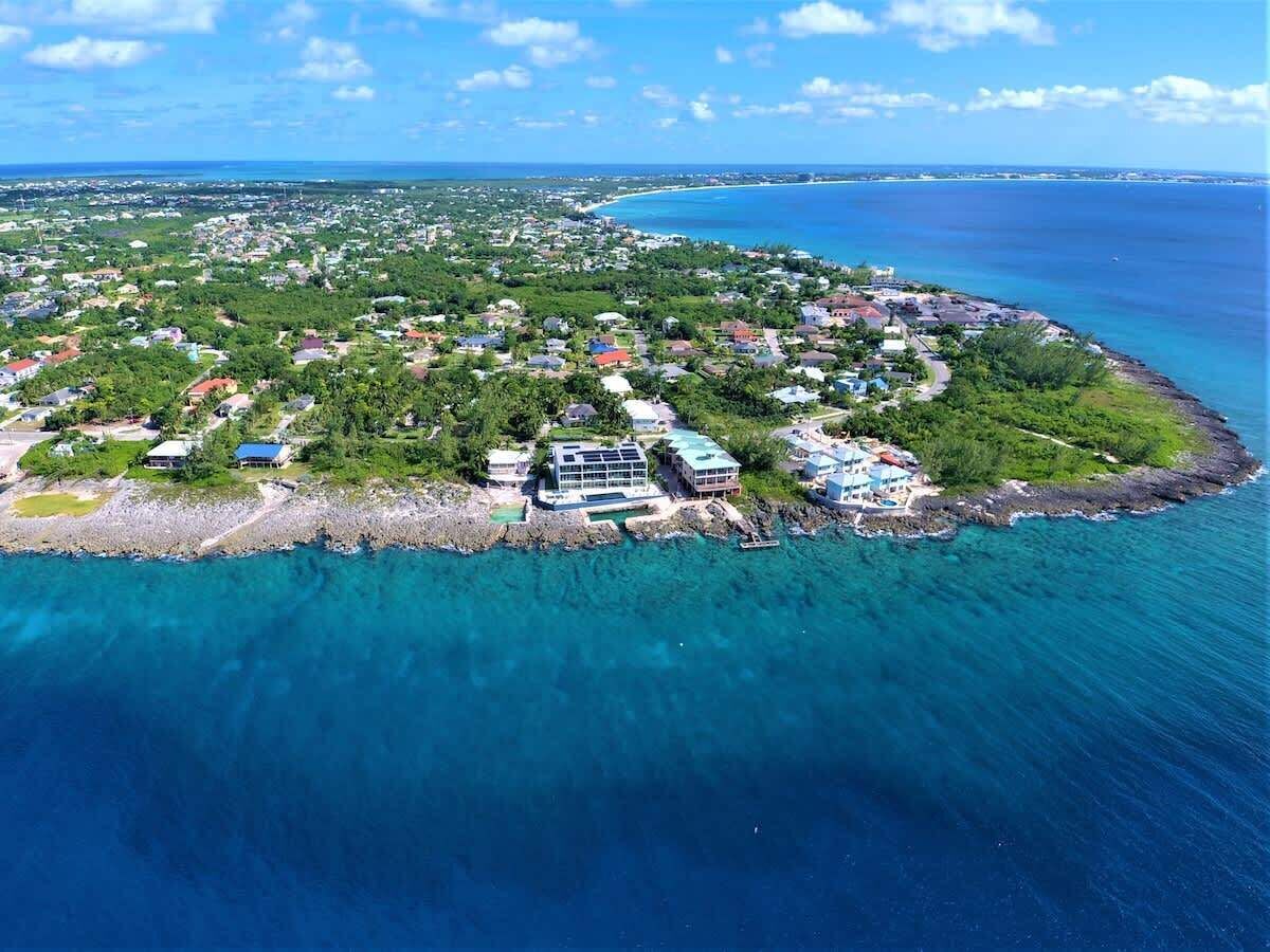 Luchtbeeld van een kustplaats met huizen, een jachthaven en helderblauw water.