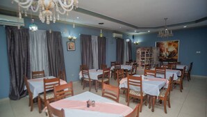 Zona pranzo con diversi tavoli e sedie, condizionatori e un lampadario.