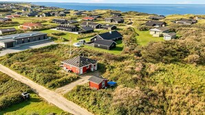An aerial view of a coastal residential area with houses, a road, and a body of water in the background. - 5 Star Holiday Home in Lokken (Lokken)