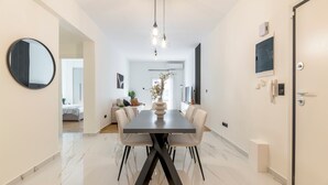 A modern dining area with a marble floor, a dark wooden table, and white upholstered chairs. - Adorable 2BR Apartment in Neos Kosmos (Athina)