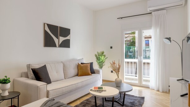 A modern living room with a sofa, coffee table, and a plant. - Adorable 2BR Apartment in Neos Kosmos (Athina)
