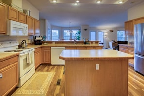Una cocina con armarios de madera, una isla central, estufa y lavavajillas.