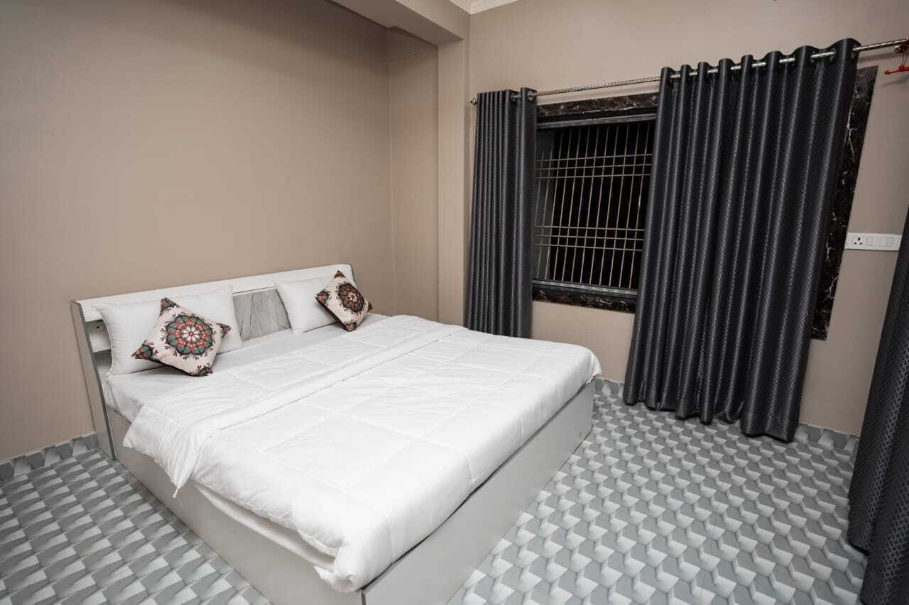 A bedroom with a bed, a window with curtains, and a patterned floor.