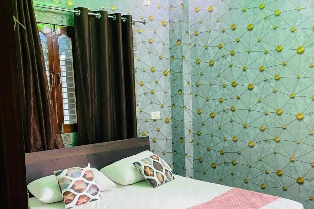 Un dormitorio con cama, cortinas y pared decorada.