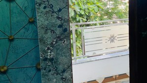 Vista a través de un vano con pared decorativa, balcón con piso de baldosas y cercado con panel ornamental.