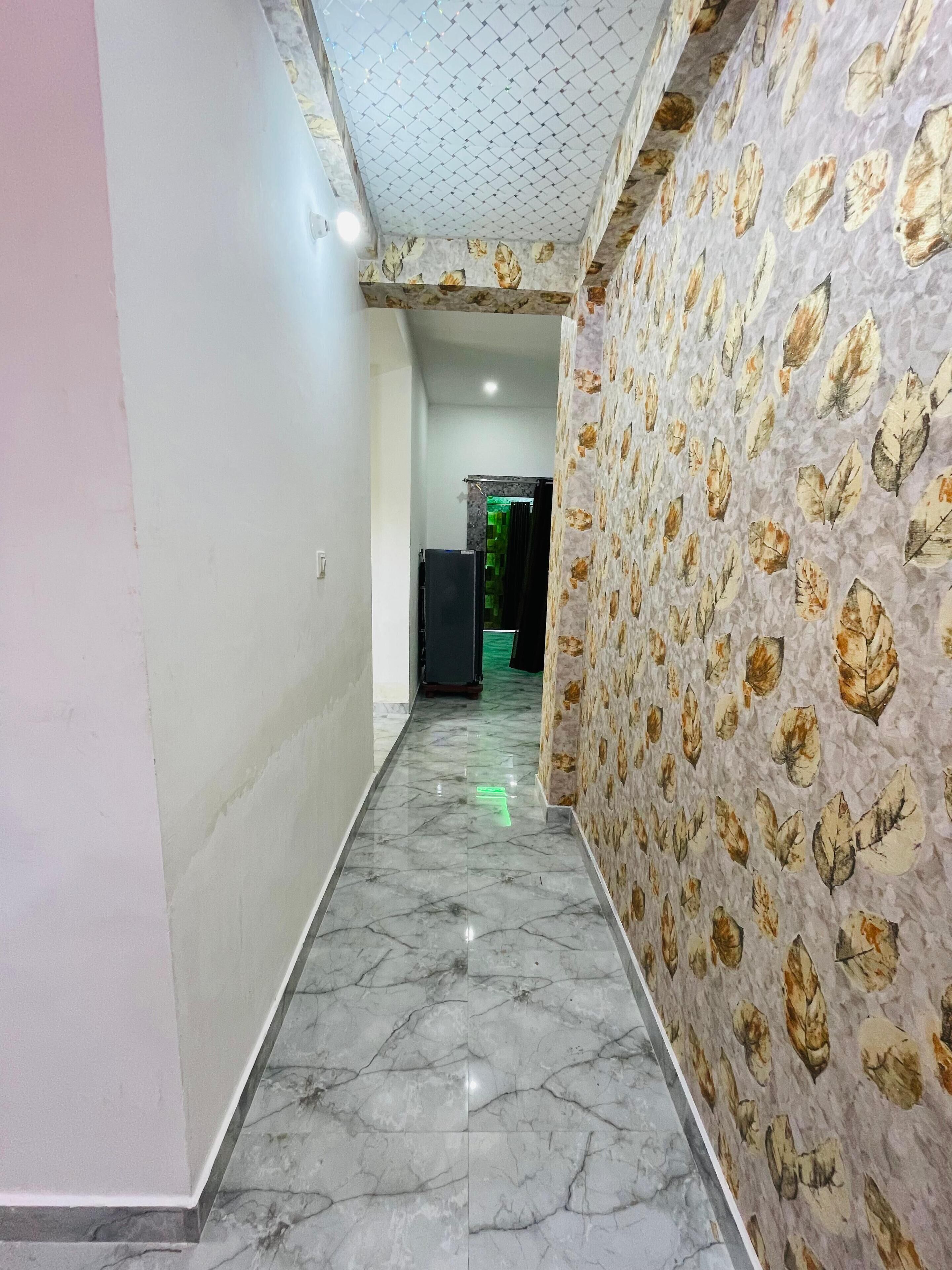 A hallway with a marble floor, patterned wallpaper, and a ceiling with a grid design.