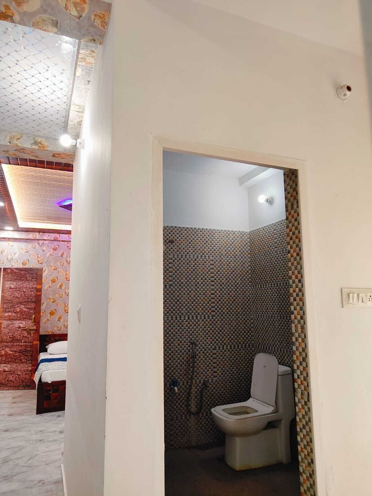 Une salle de bain avec un mur de douche carrelé, des toilettes et un pommeau de douche.