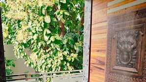 Una habitación con suelo de baldosas, puerta de madera con adornos y balcón con barandilla de metal.