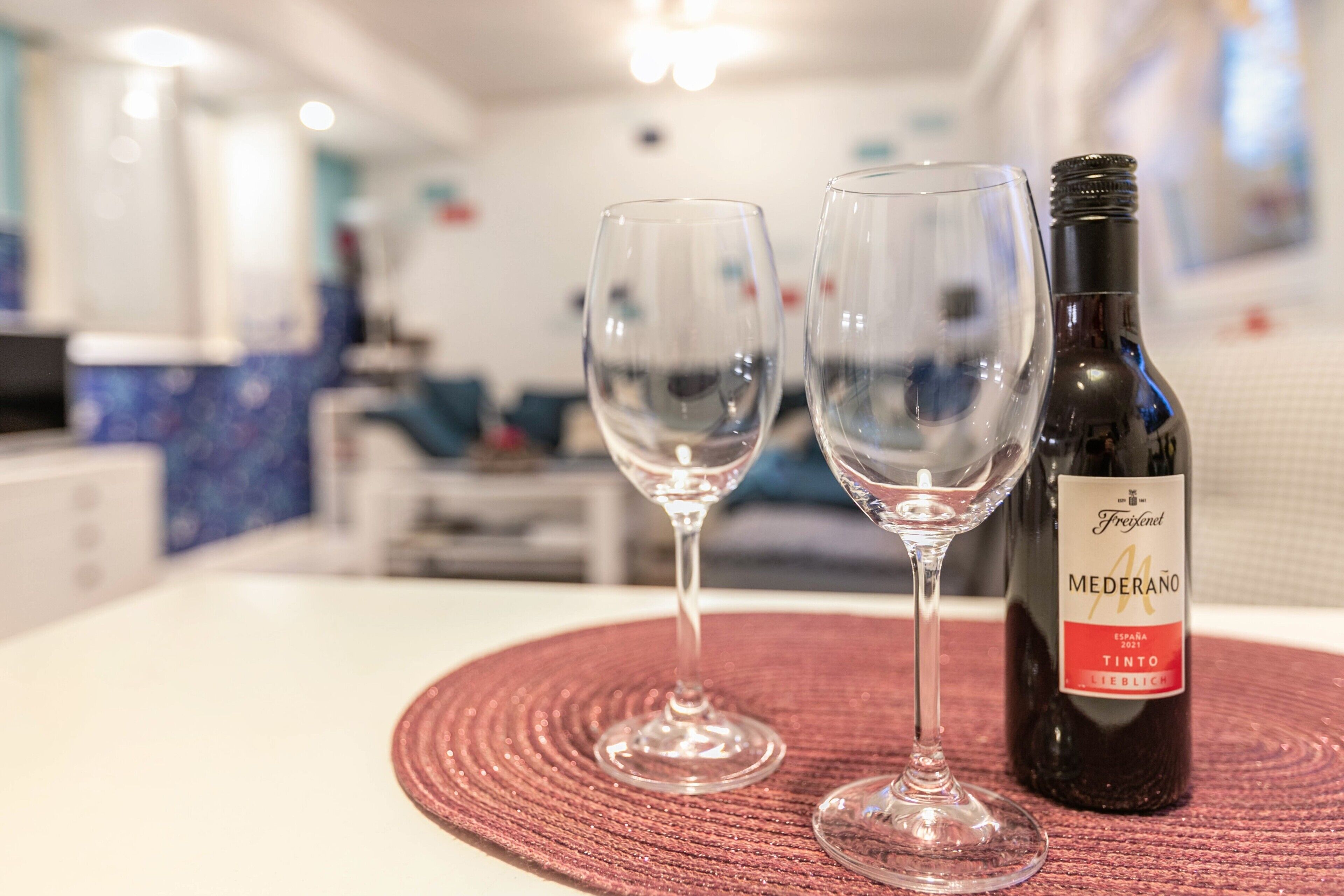 Two empty wine glasses on a table with a bottle of wine.