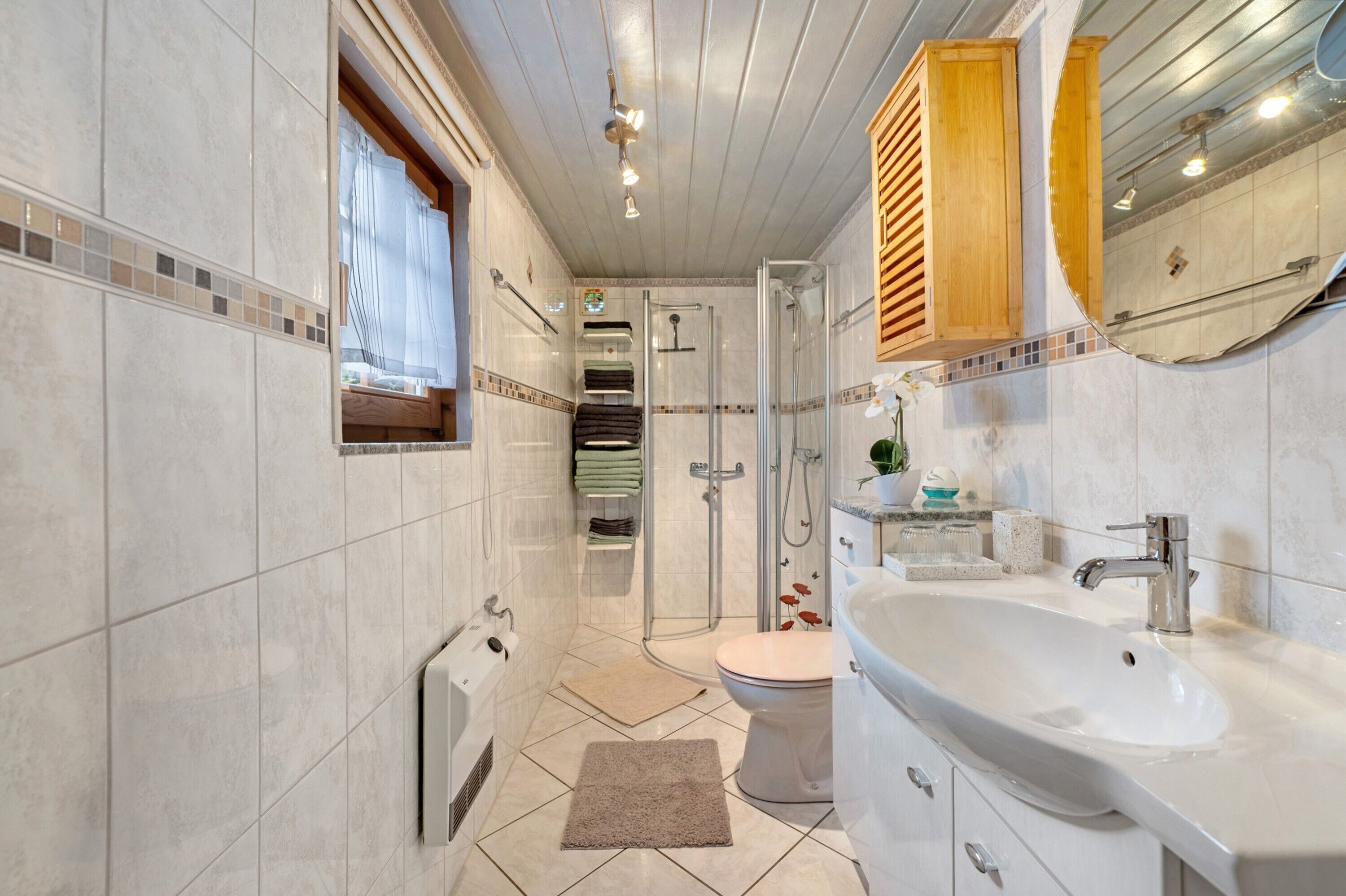 A modern bathroom with a glass shower enclosure, a white sink, and a toilet.