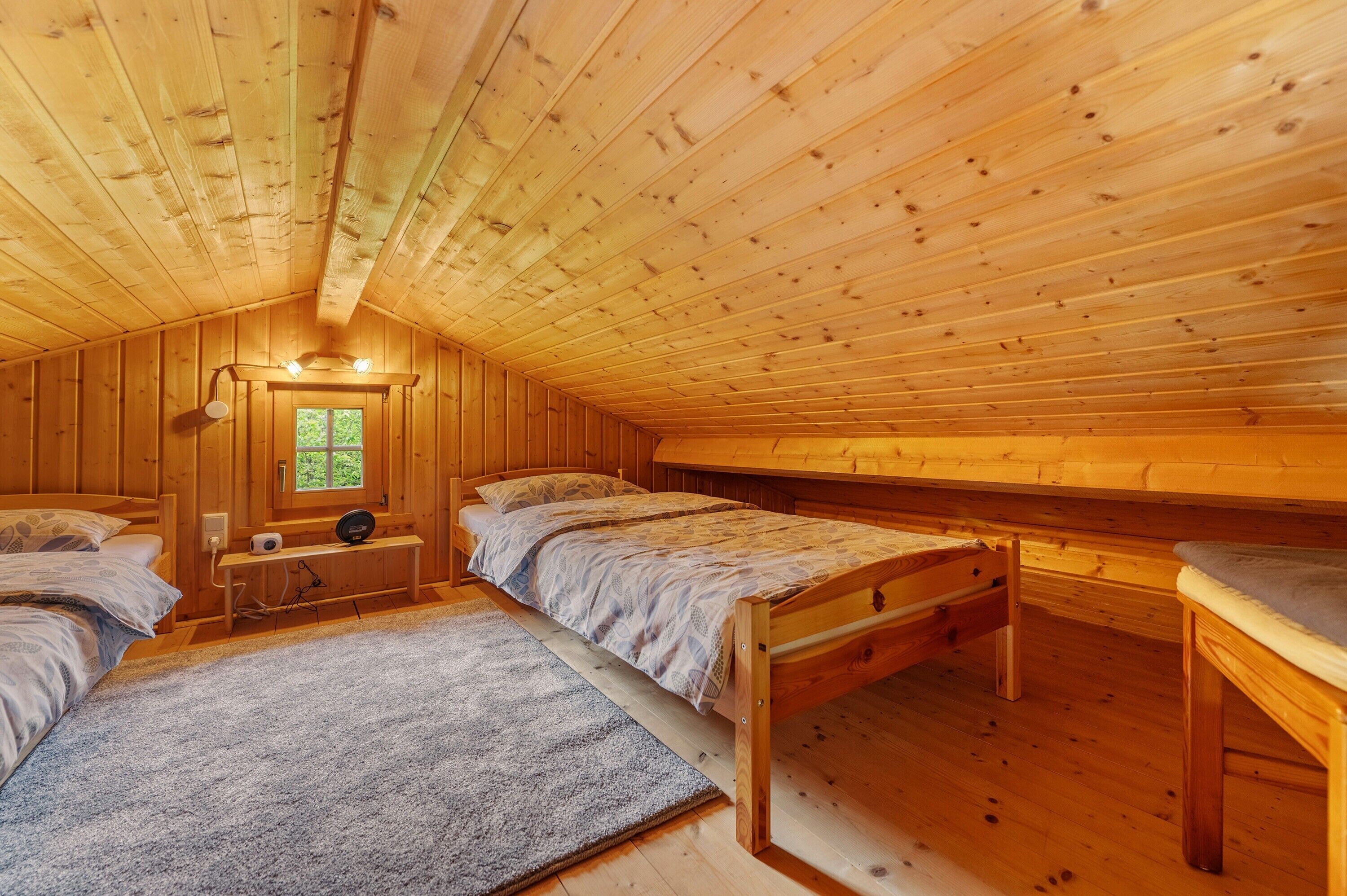 A cabin with three wooden beds, a window, and a ceiling light fixture.