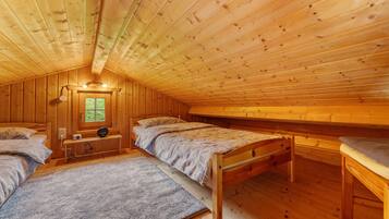 A cabin with three wooden beds, a window, and a ceiling light fixture.