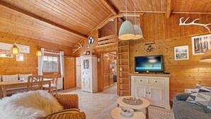 Un intérieur en bois comprenant un coin repas, un canapé, un téléviseur et une cheminée.