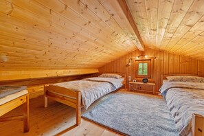 A wooden cabin bedroom with two beds, a window, and a small table. - Holiday Home 'Moi Holzhaisel' with Private Terrace, Private Garden and Wi-Fi (Elmstein)