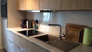 Una cocina moderna con un lavamanos de acero inoxidable, armarios de madera y una cafetera.