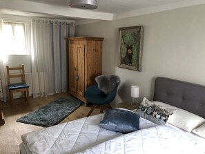 A bedroom with a bed, a chair, a wardrobe, a painting, and a lamp. - Holiday Home 'An Der Truse' with Shared Terrace, Private Garden and Wi-Fi (Brotterode-Trusetal)
