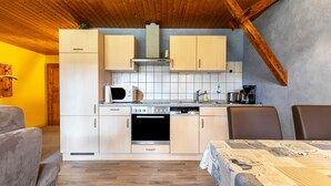 Una cocina compacta con armarios de madera, microondas, horno y cafetera.