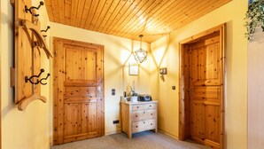 Un pasillo con puertas de madera, un aparador y una lámpara colgante.