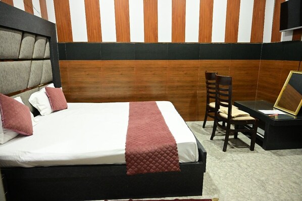 Una habitación de hotel con cama, escritorio, silla y televisión.