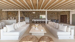 A spacious lounge area with white sofas and a central coffee table, stone walls, and a wooden ceiling. - Villa in Kalafati with 8 bedrooms sleeps 16 (Kalafati)