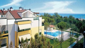 A modern residential complex with a pool and a view of the sea.