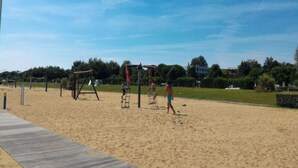 Una platja sorrenca amb una passera de fusta i aparells de jocs.