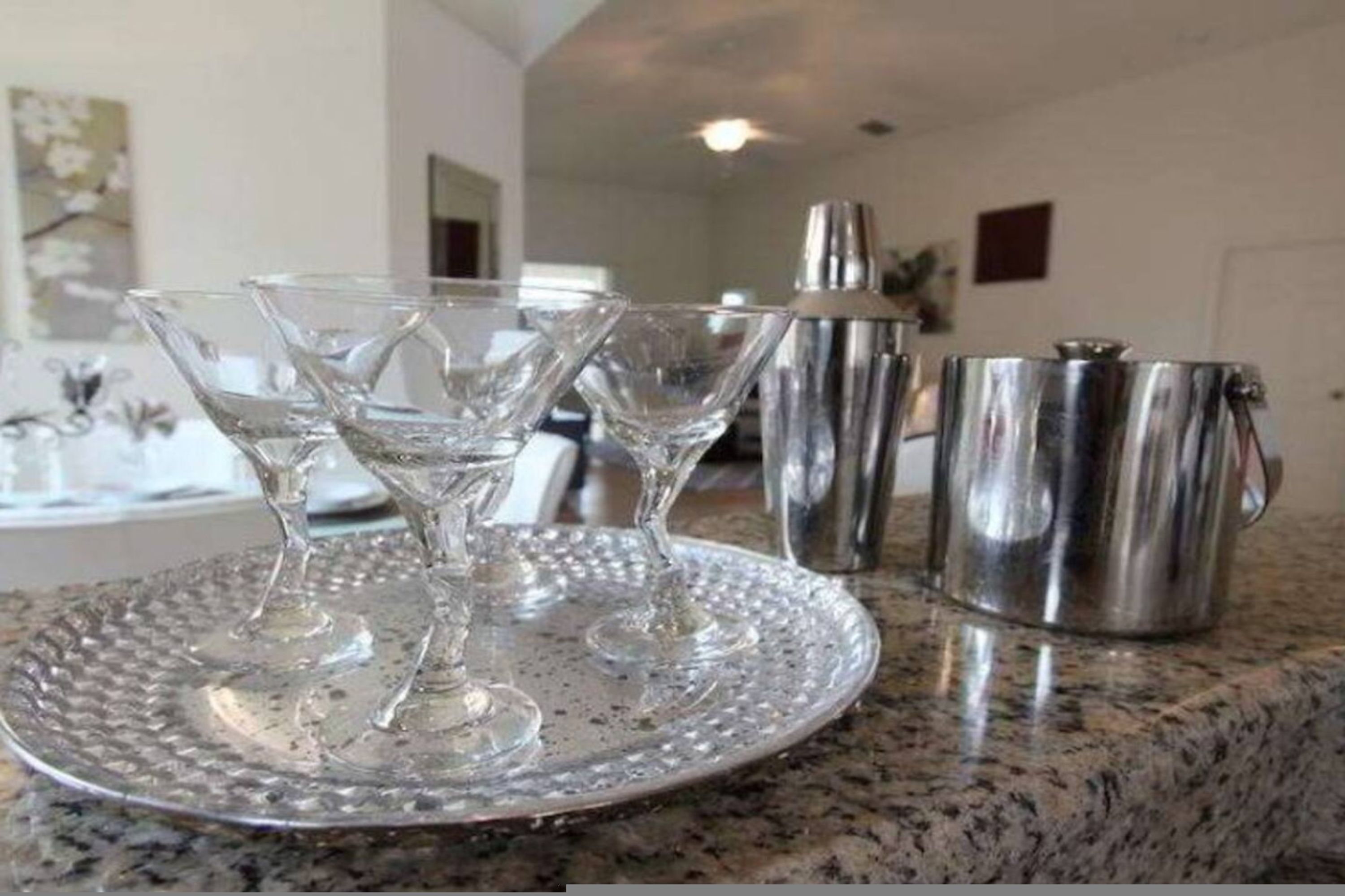 Un piano di lavoro in cucina con tre bicchieri di cristallo e due brocche di metallo.
