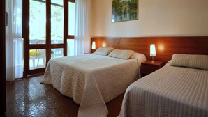 Ein Hotelzimmer mit zwei Betten, einem Holzkopfteil, einem Bild an der Wand und Blick durch eine Glastür.