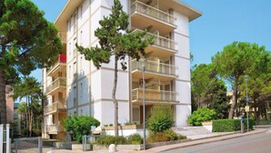 Un immeuble résidentiel à plusieurs étages, doté de balcons et entouré d’arbres et de verdure.