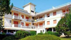 Un immeuble à plusieurs étages doté de balcons, d’une cour intérieure et entouré de verdure.