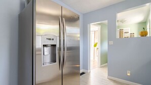 Una cucina moderna con frigorifero in acciaio inossidabile, erogatore d'acqua integrato e parete azzurra.