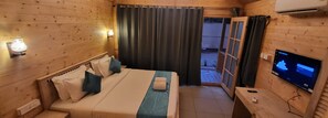 Ein Zimmer in einer Holzhütte mit einem Bett, einem Fernseher und einem Fenster mit Vorhängen.