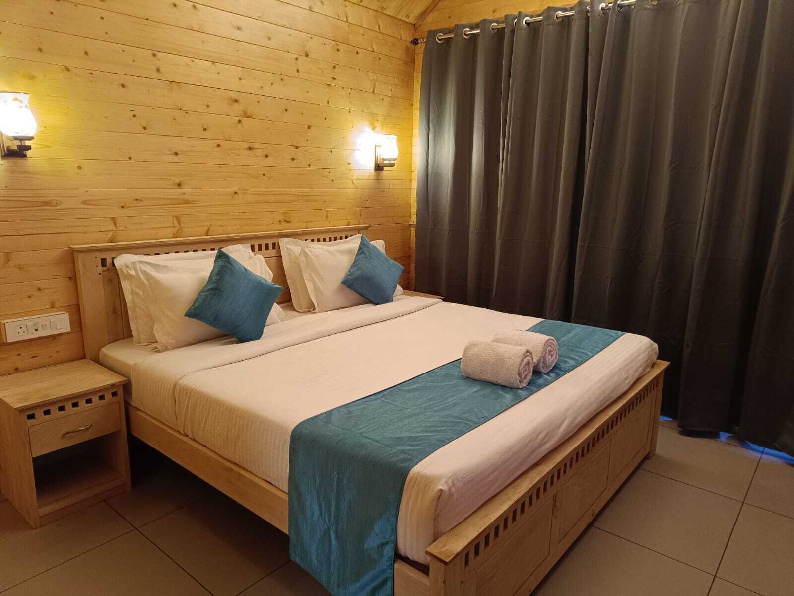 Una habitación con paneles de madera, una cama, mesitas de noche y una cortina.