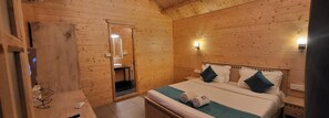Ein Schlafzimmer einer Holzhütte mit Bett, Nachttischen, einem Spiegel und einem kleinen Badezimmer.