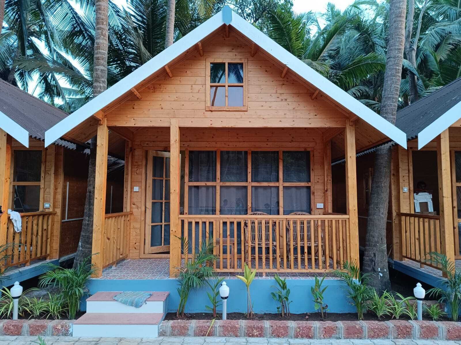 Une cabane en bois avec un toit à deux versants, de grandes fenêtres et une véranda dotée d’une balustrade.