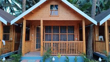 Une cabane en bois avec un toit à deux versants, de grandes fenêtres et une véranda dotée d’une balustrade.