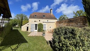Une maison en pierre avec un patio carrelé, une porte et une cheminée.
