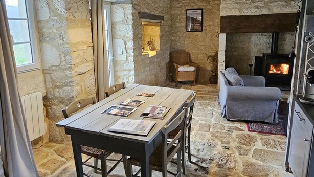 Un intérieur rustique en pierre avec une table à manger, un canapé et une cheminée.