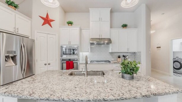A modern kitchen with white cabinetry, stainless steel appliances, granite countertops, and pendant lighting. - Cozy Home Luxury Corporate Housing (Lewisville)