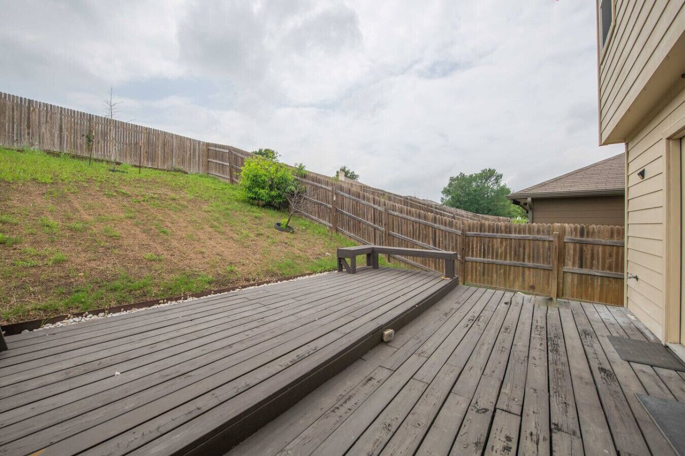 Une terrasse en bois avec une rampe menant à une maison.