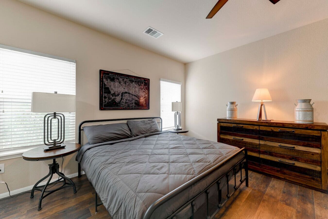 Un dormitorio con cama, mesitas de noche, cómoda y un cuadro en la pared.