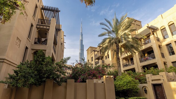 A residential area with modern buildings, a prominent skyscraper in the background, and lush greenery. - Maison Privee - Stylish & Spacious Apartment in Downtown Dubai (Dubai)